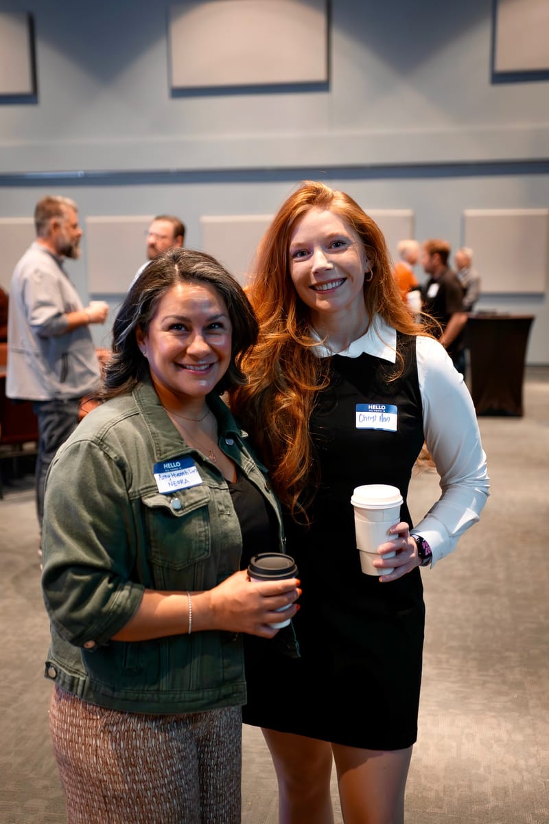 Cheryl Ann and another attendee wearing name tags and holding coffee at a Seattle networking gathering